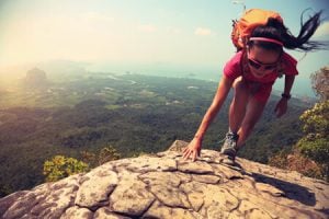 Woman climbing mountain with orange backpack